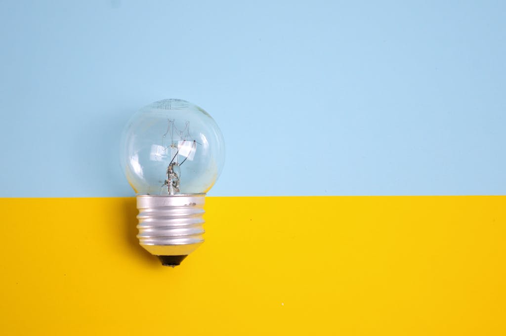 A clear light bulb against a vibrant blue and yellow background, symbolizing energy and creativity.